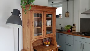 A kitchen with a wooden cabinet, a black floor lamp, and a window with a view of the outdoors. - Beautiful detached house in an oasis of calm, close to beach and sea. (Koudekerke)