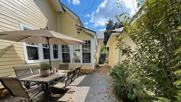 Une terrasse avec une table et des chaises, un pot de fleurs et un espace abrité.