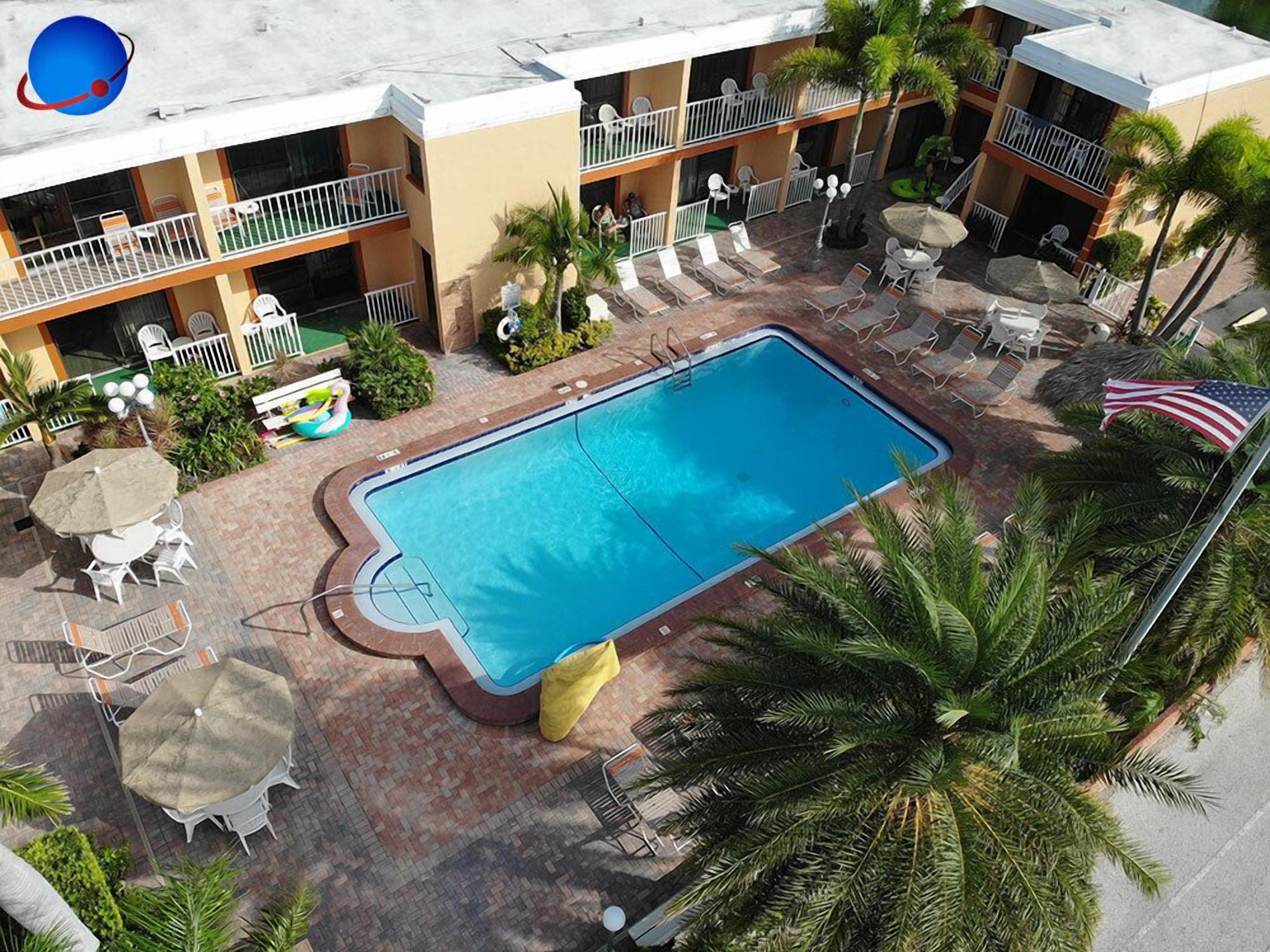 A hotel with a swimming pool, outdoor seating, and a two-story building.