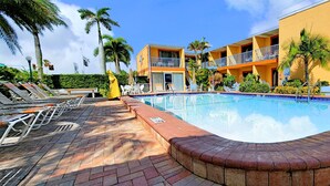 A swimming pool with lounge chairs and a building with balconies.