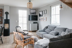 A living room with a fireplace, a sofa, a chair, and a television on the wall.