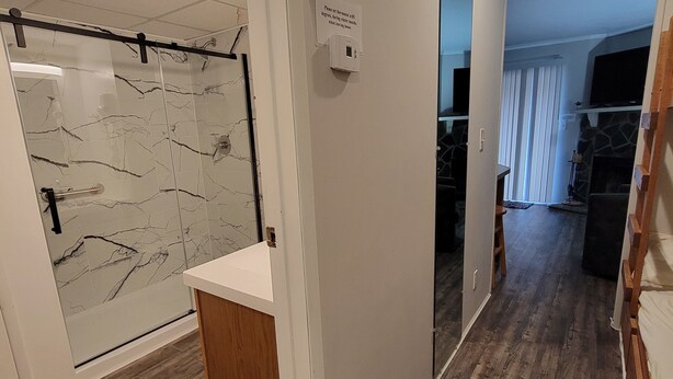Ein modernes Interieur mit Holzboden, einer Duschkabine aus Glas und einer weißen Tür mit einem Schild.