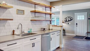 A modern kitchen with white cabinets, wooden shelves, and a stainless steel sink. - Spacious 5BR with Sauna & AC, Fenced Yard,Fast WiFi, Near Willamette Pass (Oakridge)
