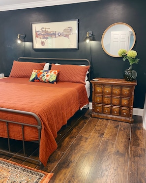 A bedroom with a bed, a dresser, a mirror, and a framed picture on the wall.
