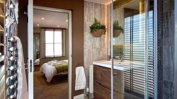 Une salle de bain moderne avec une douche à parois de verre, un meuble-lavabo en bois et un grand miroir.