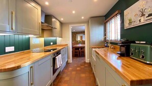 Une cuisine moderne avec des plans de travail en bois, des appareils électroménagers intégrés et une vue sur la salle à manger.