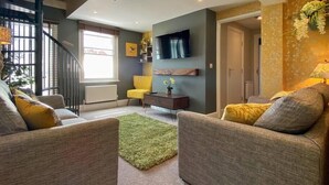 Un salon moderne avec un escalier, un téléviseur à écran plat et un coin salon confortable.