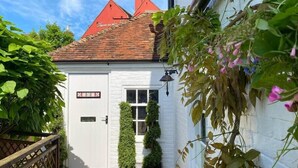 Un bâtiment blanc avec un toit recouvert de tuiles rouges, une porte avec une enseigne et une petite fenêtre.