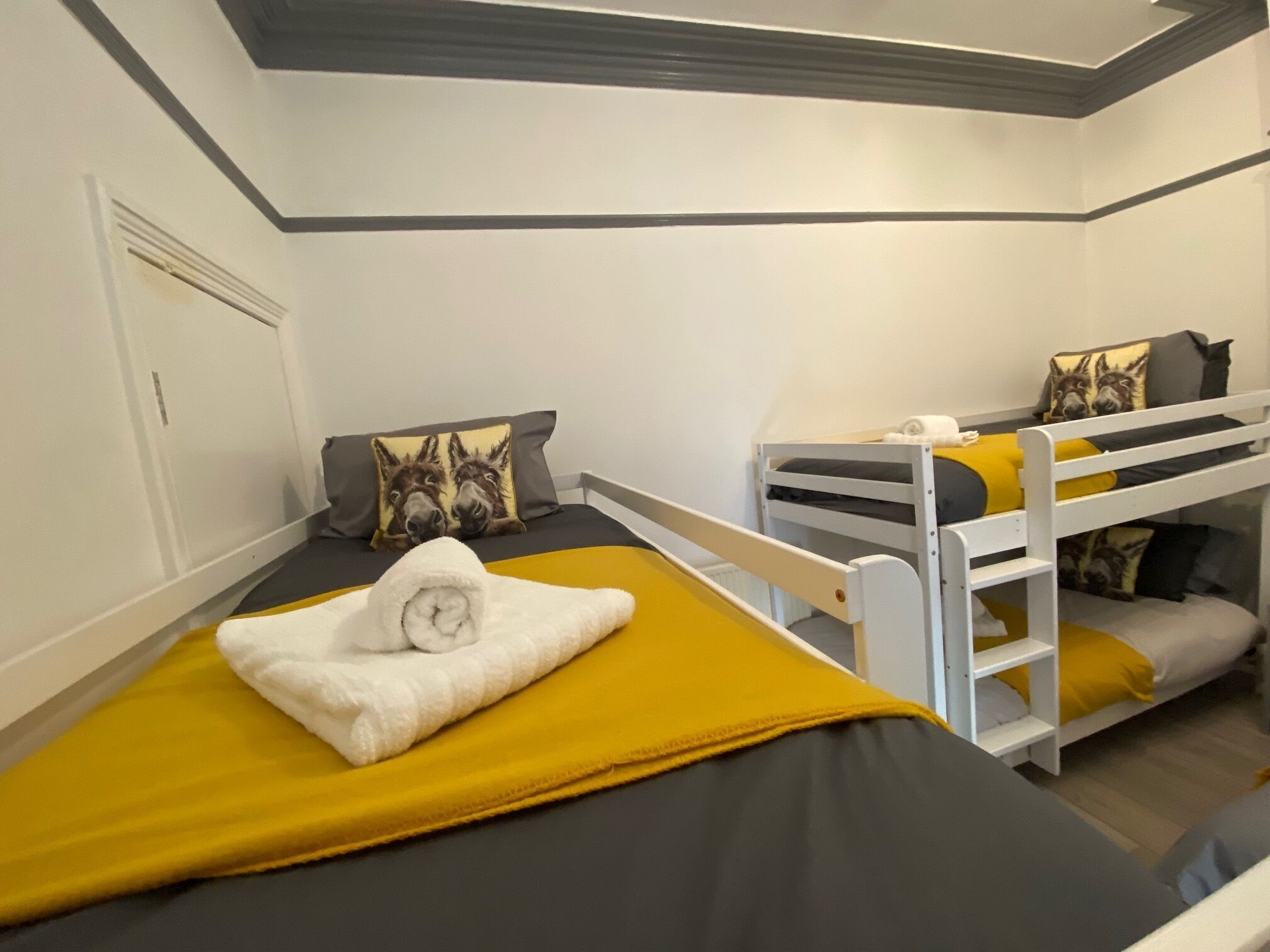 Een slaapkamer met een stapelbed, een gele deken en een opgerolde handdoek op het bed.