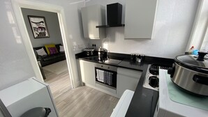 A modern kitchen with a black countertop, stainless steel appliances, and a white backsplash. - Blackpool Abode - 124 Elite Apartments (Blackpool)