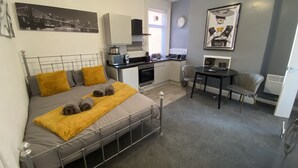 A compact room with a bed, a small kitchenette, a dining area, and a bathroom. - Blackpool Abode - 124 Elite Apartments (Blackpool)