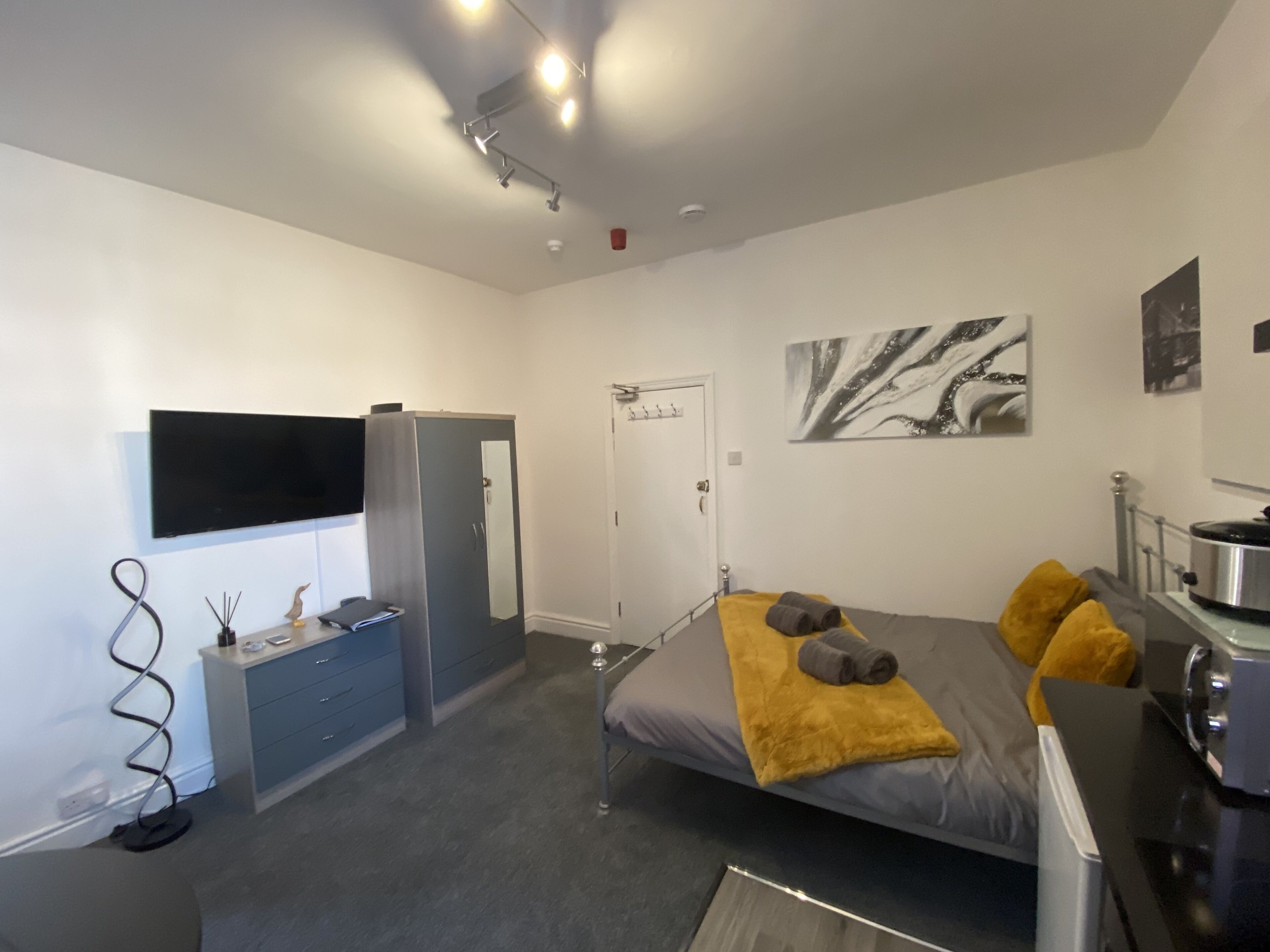 Een moderne slaapkamer met een bed, een bureau, een kledingkast en een televisie.