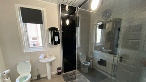 A bathroom with two toilets, a sink, a glass shower enclosure, and a window. - Blackpool Abode - 124 Elite Apartments (Blackpool)
