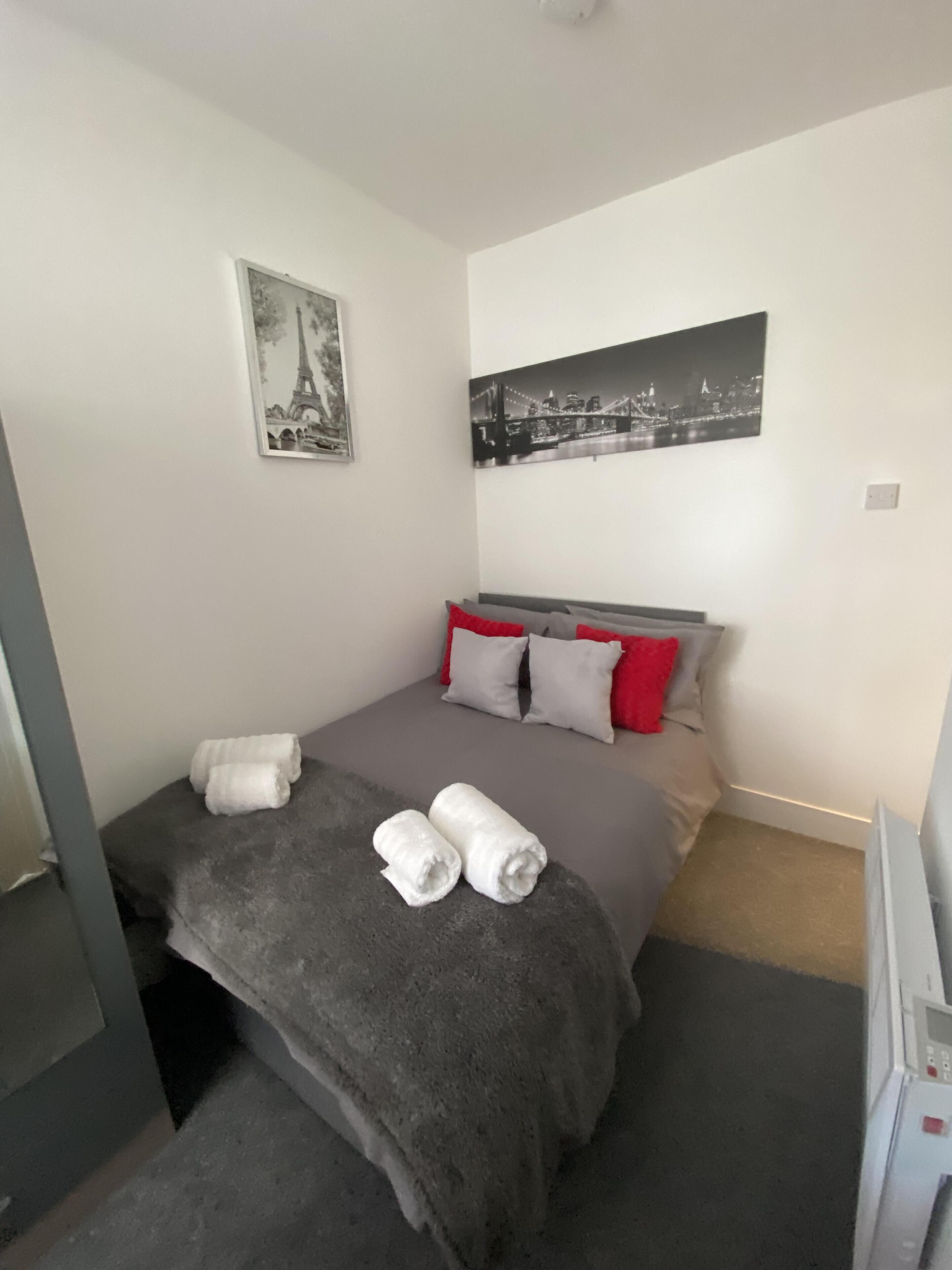 Une petite chambre à coucher, bien rangée, avec un lit, des oreillers et des serviettes.