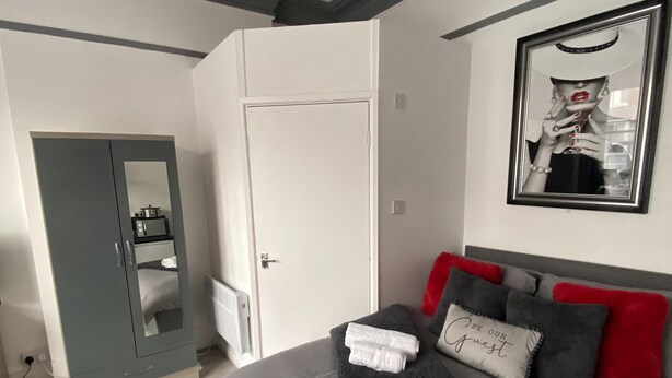 A modern bedroom with a grey bed, white towels, a grey wardrobe, and a framed picture on the wall. - Blackpool Abode - 124 Elite Apartments (Blackpool)
