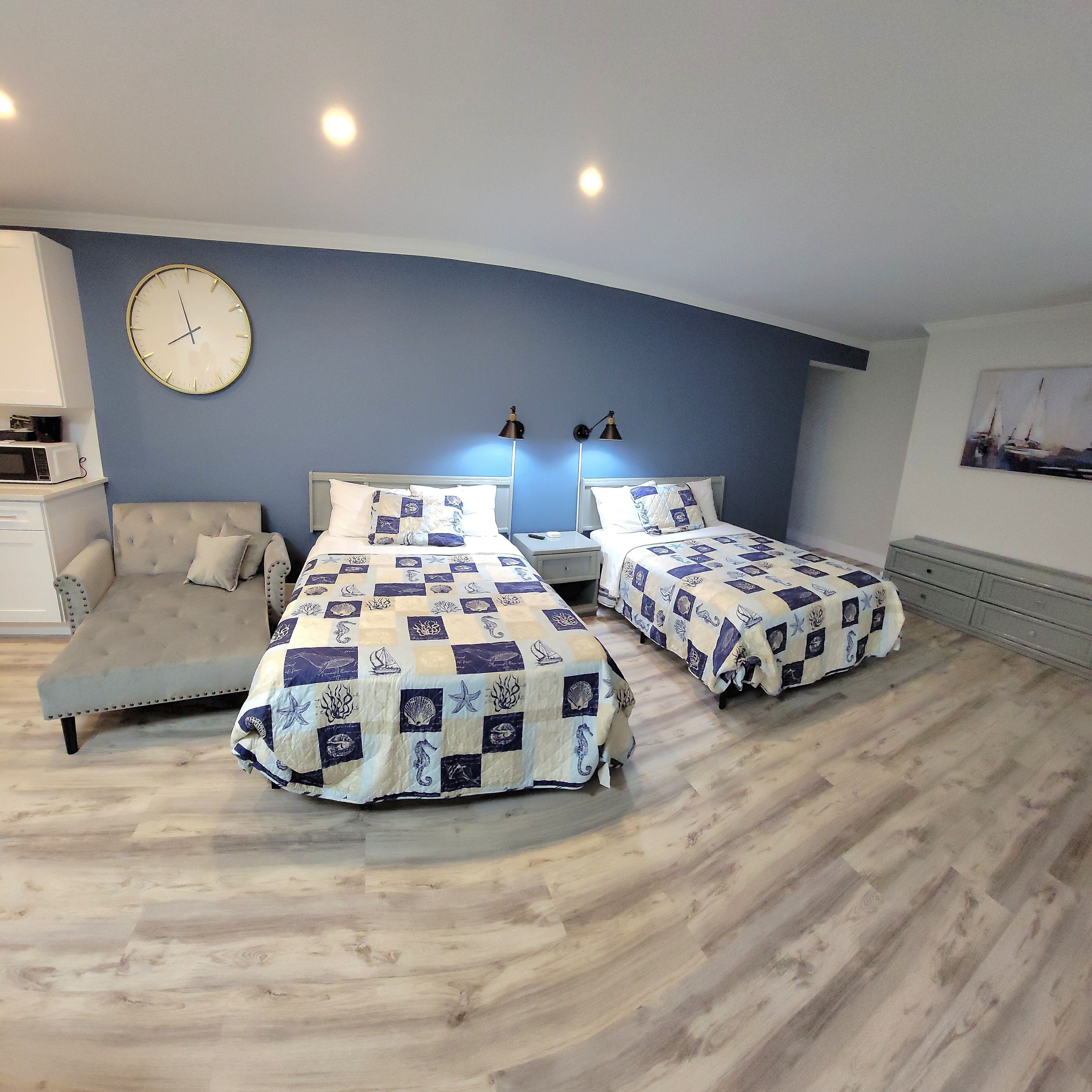 A bedroom with two beds, a sofa, a clock, and a painting on the wall.