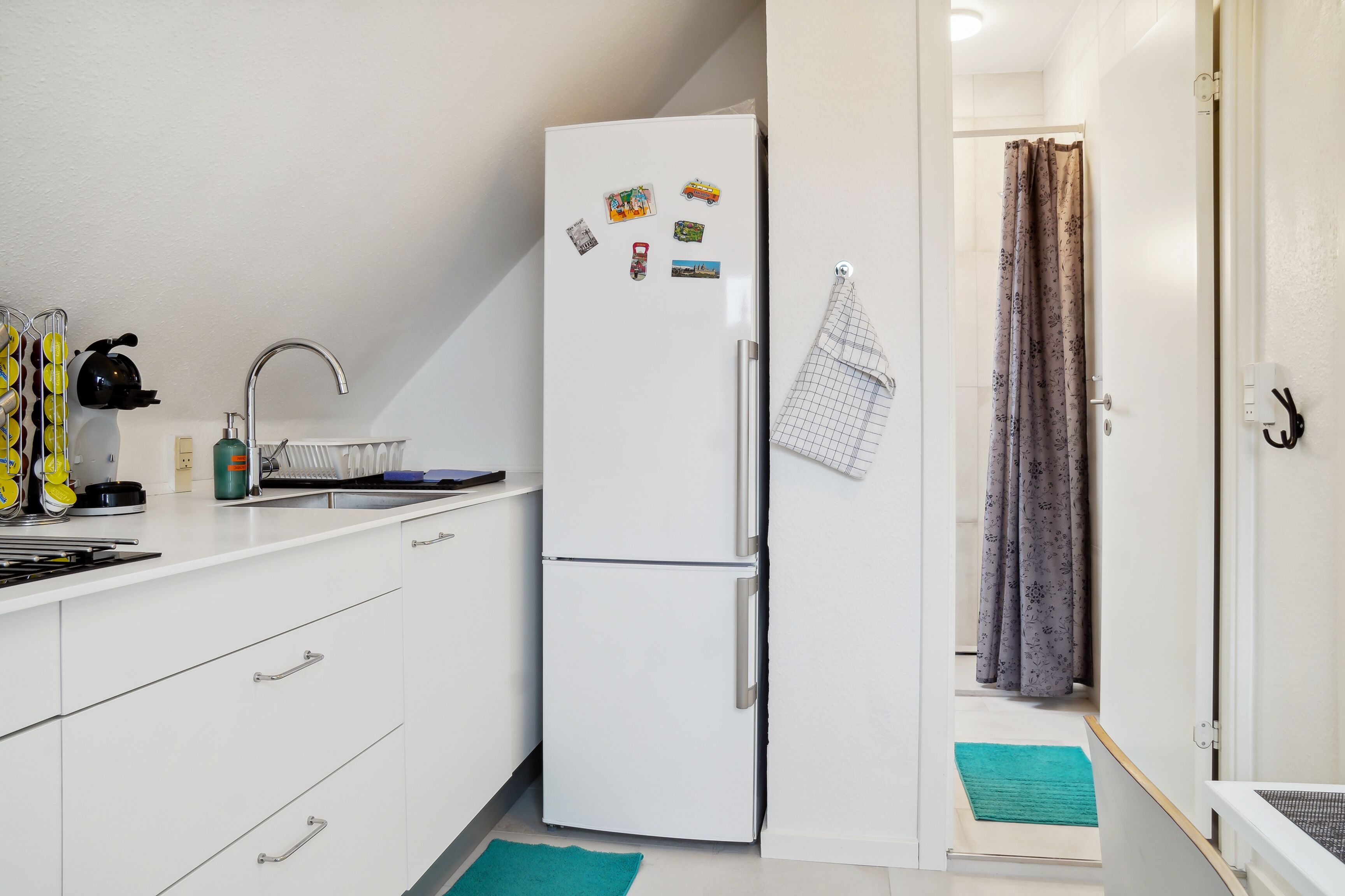 A compact kitchen with a white refrigerator, a sink, and a small countertop.