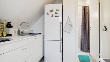 A compact kitchen with a white refrigerator, a sink, and a small countertop.