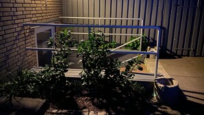 A metal gate with a metal railing in front of a brick wall.