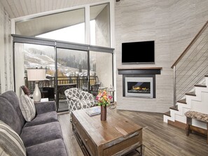 Una sala de estar moderna con chimenea, un sofá, una mesa de centro y un televisor montado en la pared.