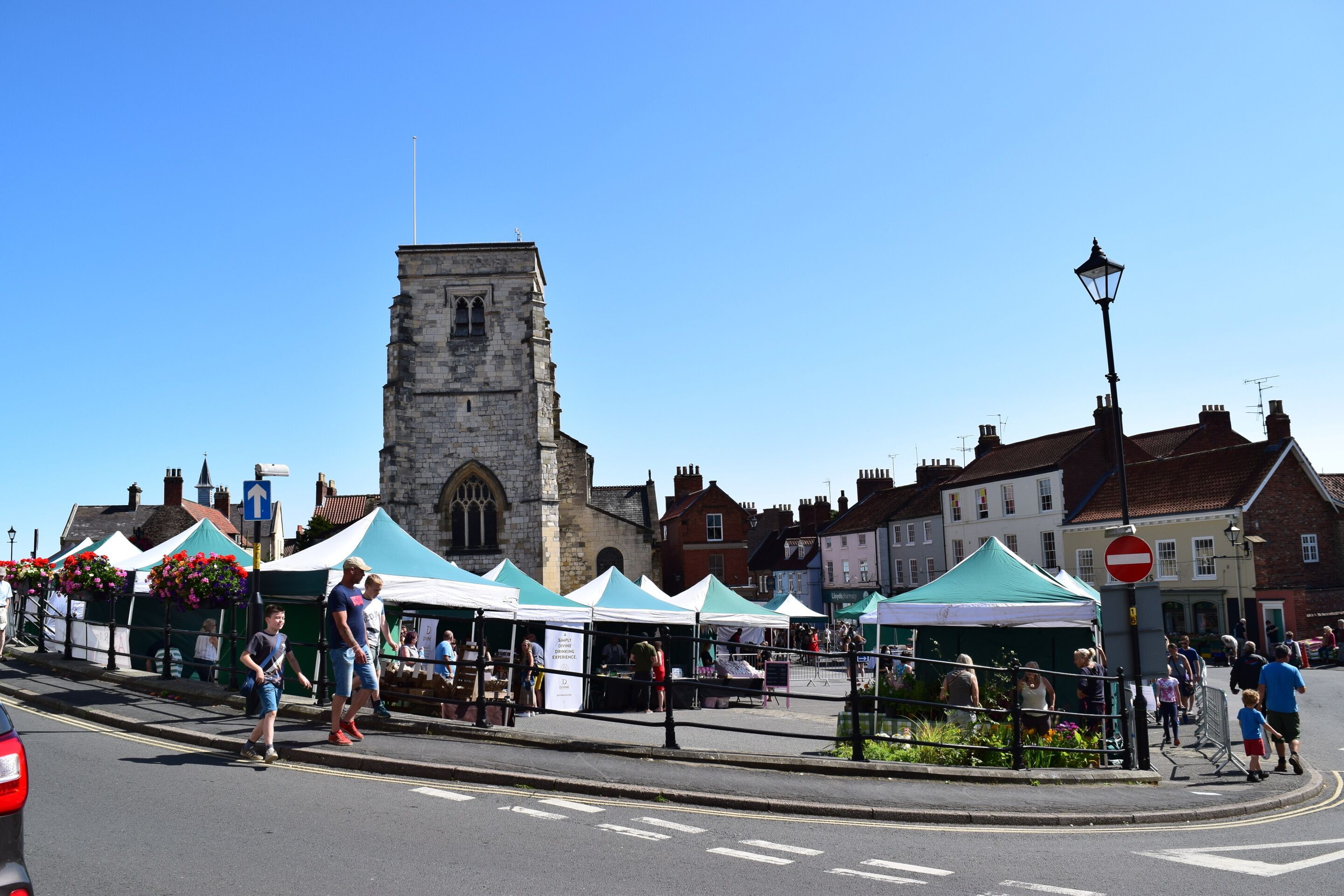 A street with market stalls, a historic tower, and traditional buildings.