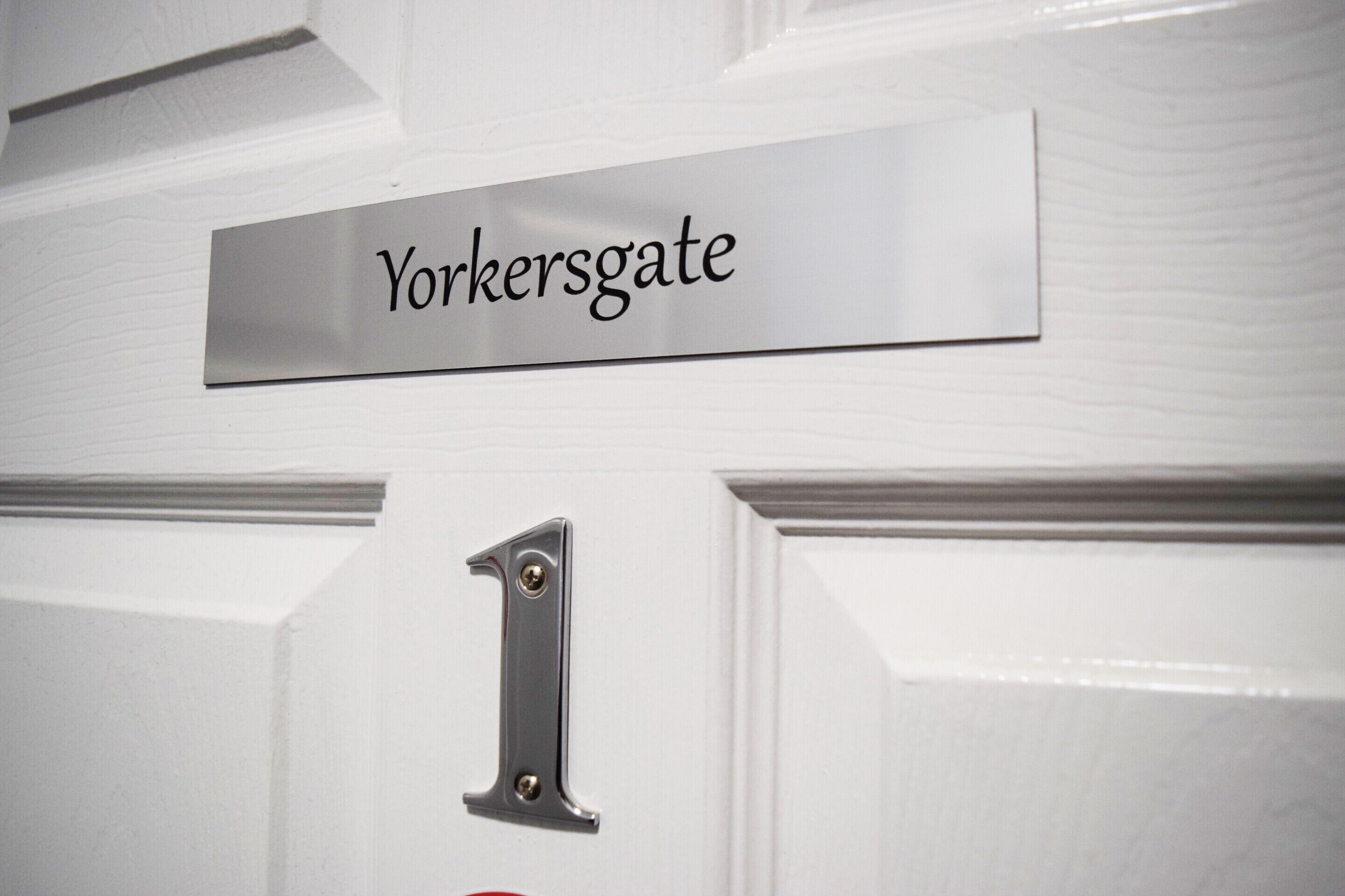 Une porte ornée d’une plaque métallique portant l’inscription « Yorkersgate » et surmontée du chiffre « 1 ».