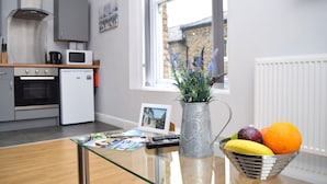 A modern kitchen with a microwave, oven, and a window with a view of a brick building. - Malton Central Apartments (Malton)