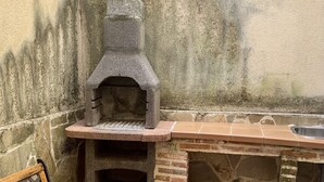 A stone-built outdoor kitchen with a built-in oven, a bench, and a sink. - Casa Rural (La Horcajada)
