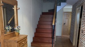 A wooden staircase with a handrail, a wooden cabinet with a mirror, and a tiled floor. - Casa Rural (La Horcajada)