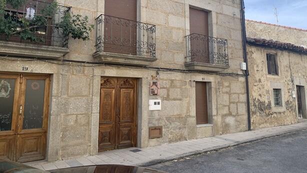 A stone building with two wooden doors, a balcony with wrought iron railings, and a small window. - Casa Rural (La Horcajada)