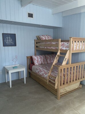A bunk bed with floral bedding, a small white table, and a framed picture on the wall.