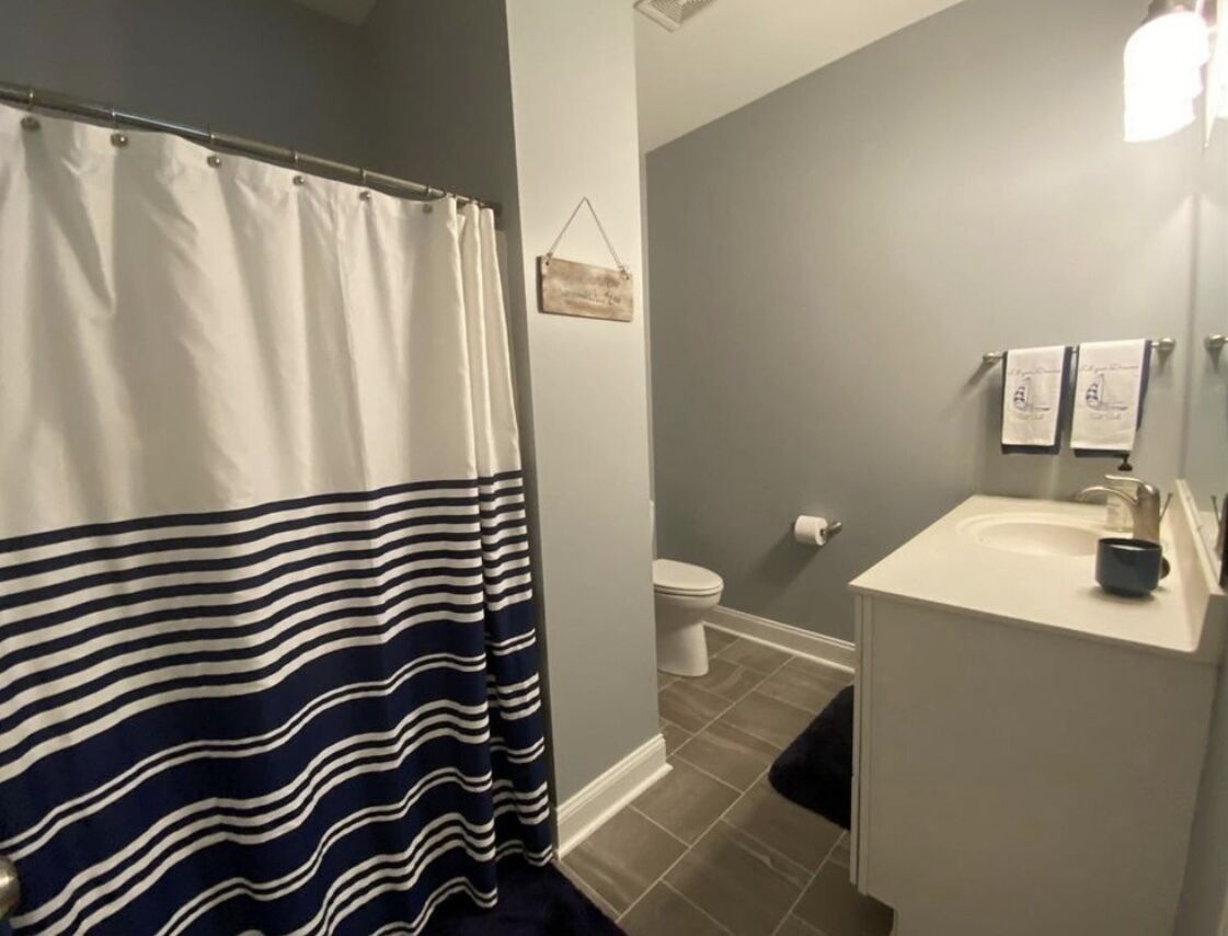 Une salle de bain avec un rideau de douche à rayures, des toilettes et un lavabo avec un miroir.