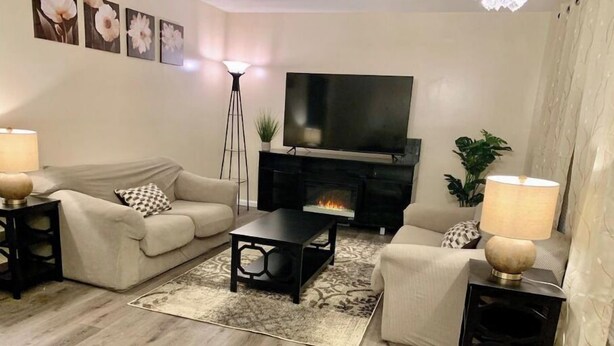 Un saló amb sofà, butaca, taula de centre, televisió, llar de foc i làmpades decoratives.