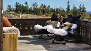 A wooden deck with two lounge chairs, one with white fur throws and the other with a black cushion. - Ski-in/ski out at Lifjell . Perfect Place for Hikes in the Mountains (Vestfold og Telemark)