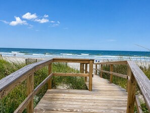 A wooden boardwalk leading to a beach with ocean views.