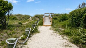 A wooden boardwalk leading to a beach with sand and greenery. - Beach Breezes - Oceanside, 4 bedrooms (Pawleys Island)