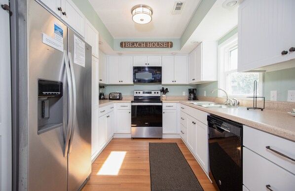 A modern kitchen with white cabinets, stainless steel appliances, a microwave, oven, and dishwasher.