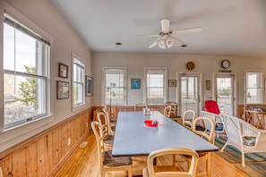 Un espace repas avec une longue table, des chaises en bois et un ventilateur de plafond.