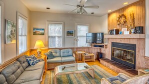Una sala de estar con sofá, sillones, una mesa de centro, televisor y chimenea.