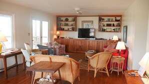 Un salon chaleureux avec un meuble en bois, un téléviseur et une bibliothèque remplie de livres et d’objets décoratifs.