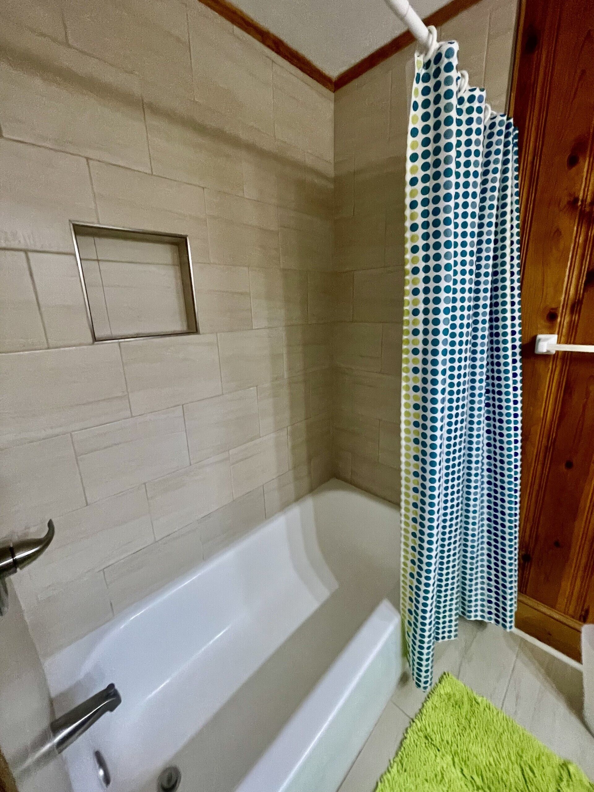 Une salle de bain avec une baignoire, un rideau de douche et une porte en bois.