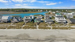 A coastal residential area with houses on stilts, a beach in the foreground, and a body of water in the background. - Allston - 4 bedrooms, Oceanfront (Pawleys Island)