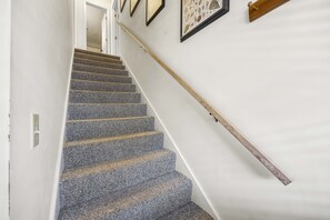 Una escalera con barandilla de madera y piso alfombrado.