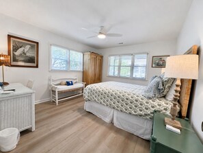 Un dormitorio con cama, escritorio, silla, armario y ventilador de techo.