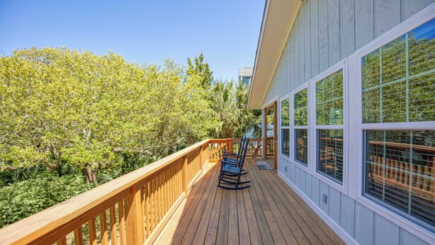 A wooden deck with a railing, overlooking a lush green landscape and a building with large windows. - Ocean Breeze - Near Ocean, 5 Bedrooms, Litchfield (Litchfield)