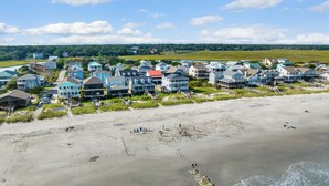 A coastal residential area with houses along the beach, a sandy beach, and ocean waves. - Schooler Shack - Oceanfront, 4 bedrooms (Pawleys Island)