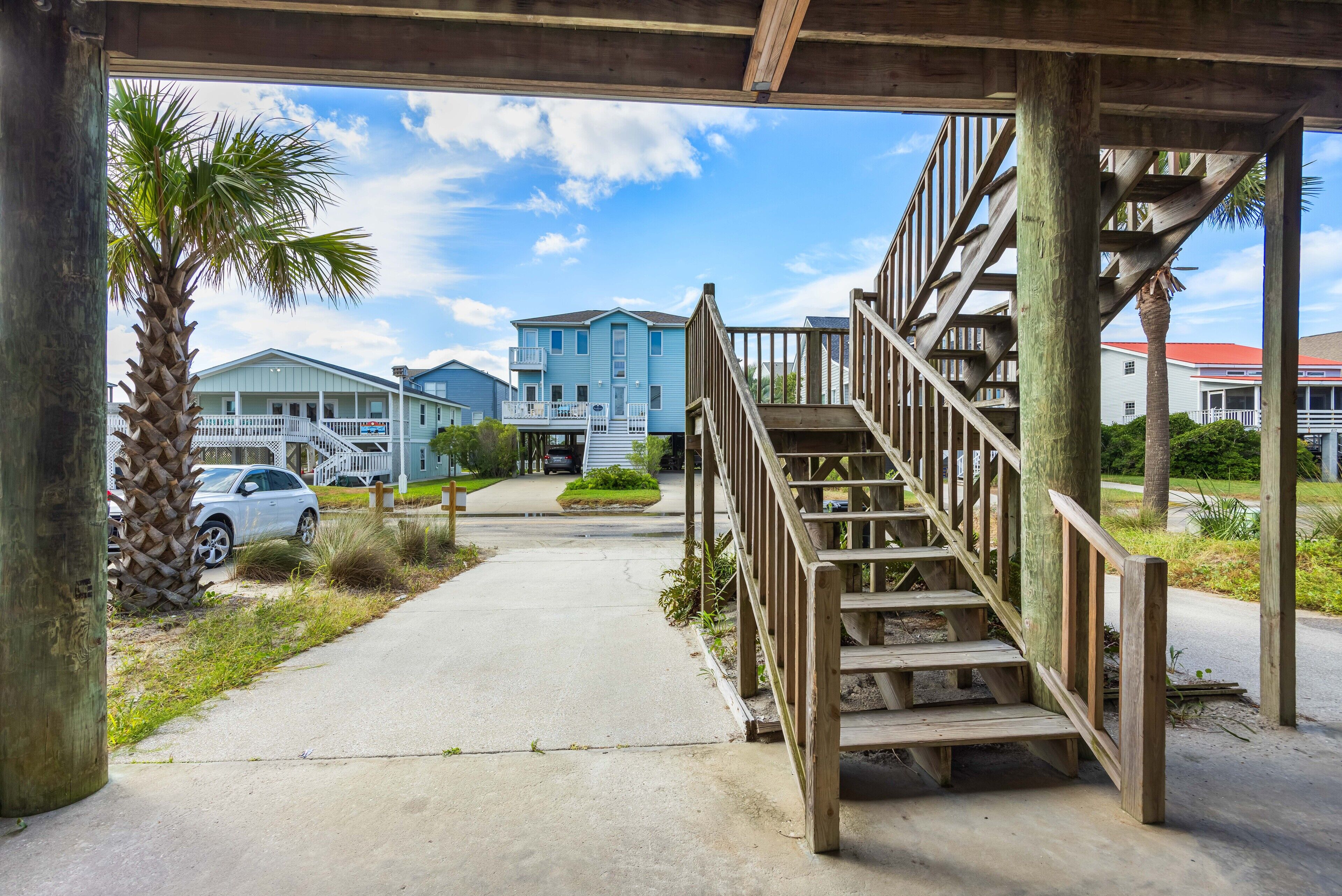 Un escalier en bois mène à une zone abritée d’où l’on peut admirer une rue résidentielle et des maisons.