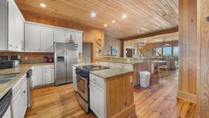 A spacious kitchen with wooden cabinets, granite countertops, and a central island.