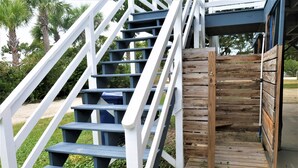 A set of outdoor wooden stairs with white railings leading to a wooden deck.