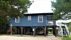 A two-story building with a balcony, a staircase, and a hammock.